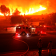 Los Angeles County firefighter looks on as the out-of-control Woolsey Fire explodes behind a house in the West Hills neighborhood on November 9, 2018 in Los Angeles, California.
